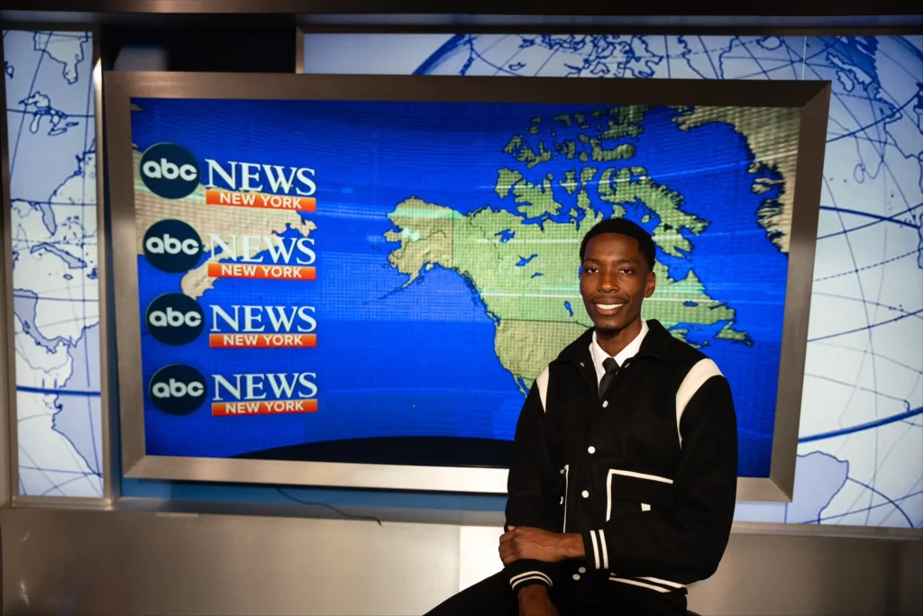 Hansely Felix, a fourth-year graphic design student, poses in front of a map of North America on the set of ABC News.