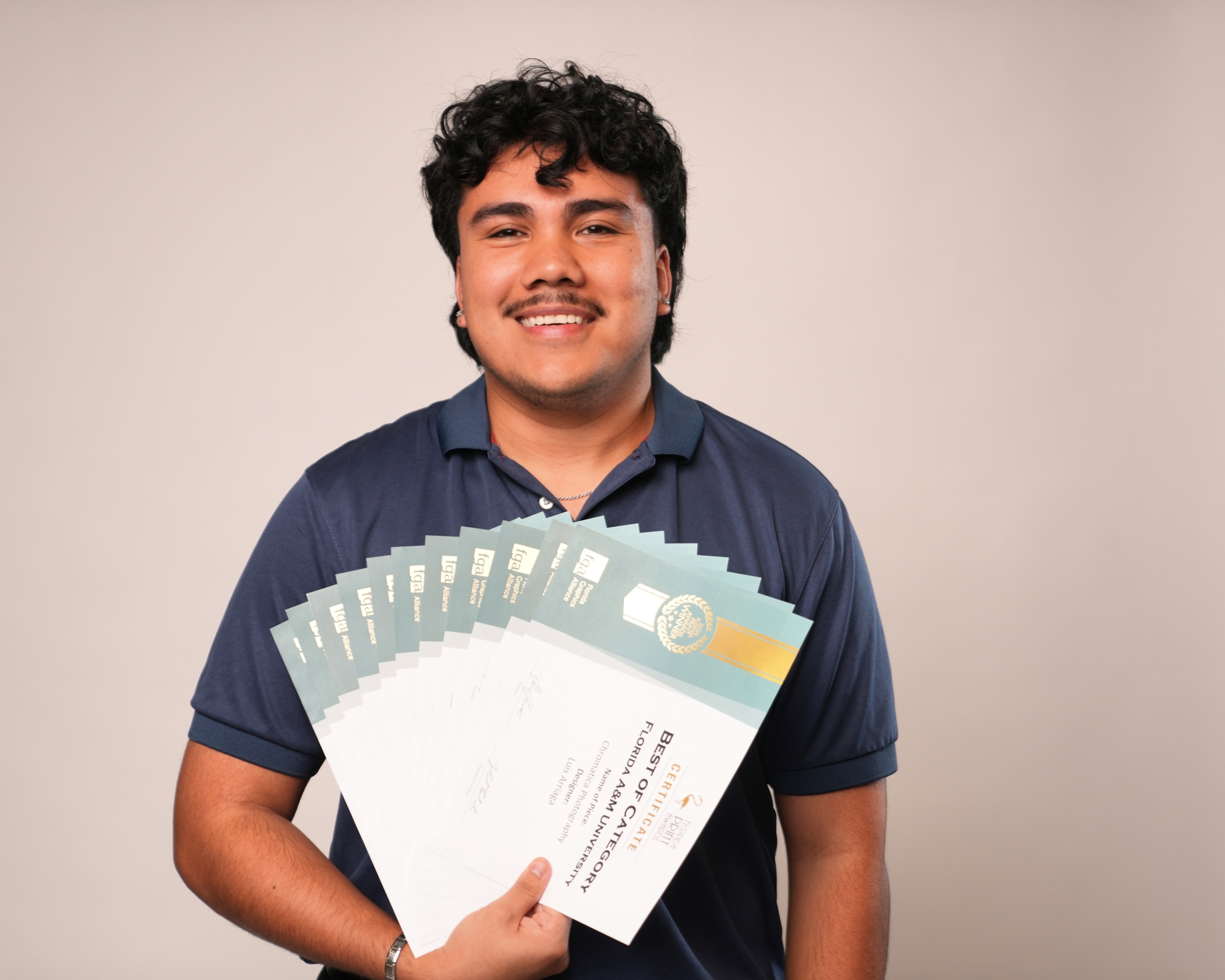 While a student in SJGC, Arriaga won multiple awards for outstanding design work. Here, he holds numerous design excellence certificates from the Florida Print Awards.