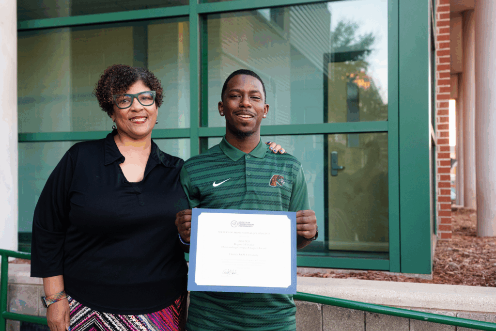 Professor Hunter and student Michael Trim Jr proudly display one of the certificates the FAMU SPJ chapter received in recognition of its accomplishments. Photo: Justyn Thomas.